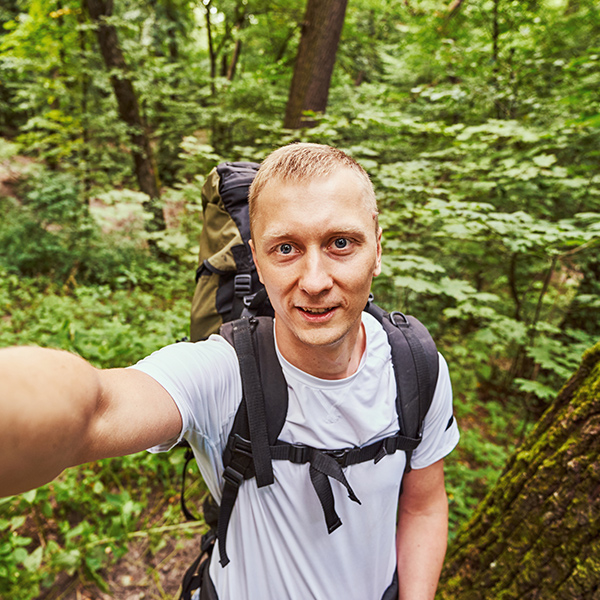 cheerful guy taking selfie in green forest KRJBFG8