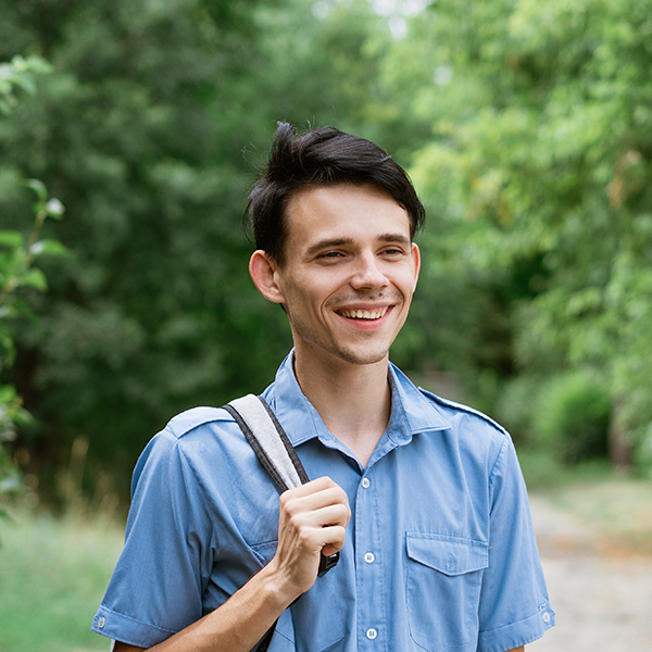 young cheerful guy student stands in a blue shirt LCUG2RR